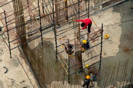 Construction workers in India climbing and building rebar platform at work site. Shows the...