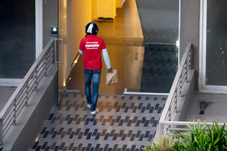 Zomato delivery person wearing the red shirt and carrying a bag for food home delivery from the indian e-com startupのeditorial素材