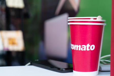Red disposable cups with zomato logo on them stacked for use at an eventのeditorial素材