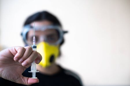 Young indian female healthcare worker doctor nurse holding a syringe with vaccine for coronavirus in...