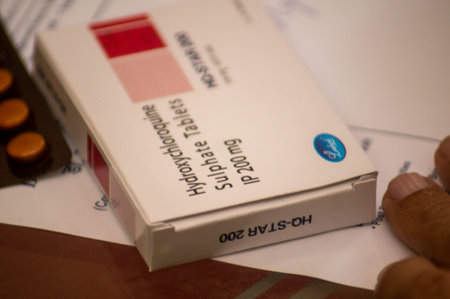 Photograph of a box and tablets of a hydroxychloroquine sulphate tablets on a piece of white...