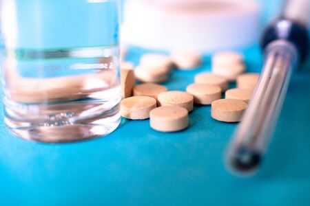 shot showing a glass ampoule, bottle, tablets, syringe, on blue background, shows the various...