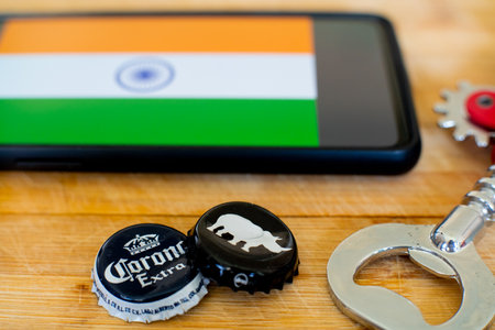 Mobile phone with india flag and two beer bottle caps and an opener on wooden boardのeditorial素材