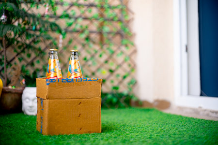 Gurgaon, Haryana, India - circa 2020 : Bottles of liquor alcohol in a cardboard box getting home delivered online kept in the garden at the threshold of a home. Shows the opening up of alcohol sector for home delivery through online startup apps due to thのeditorial素材