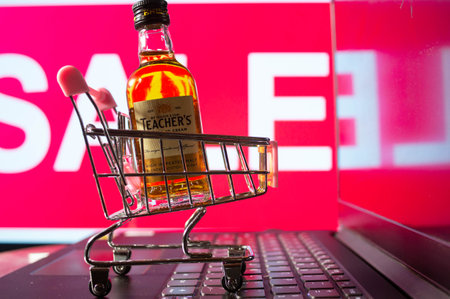 A bottle of whiskey in a trolley in front of a red sale boardのeditorial素材
