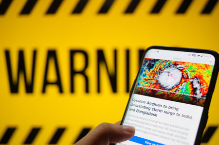 Mobile phone logged into photo of cyclone with warning backgroundのeditorial素材