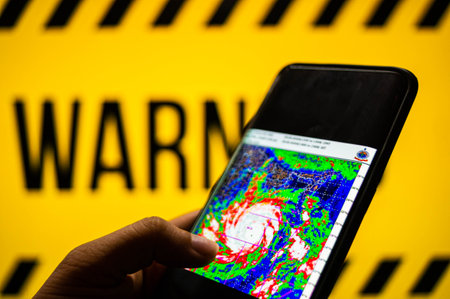 Mobile phone logged into photo of cyclone with warning backgroundのeditorial素材