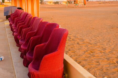Close up shot of red muddha cane chairs sofas with small yellow brick walls for seating visitors...