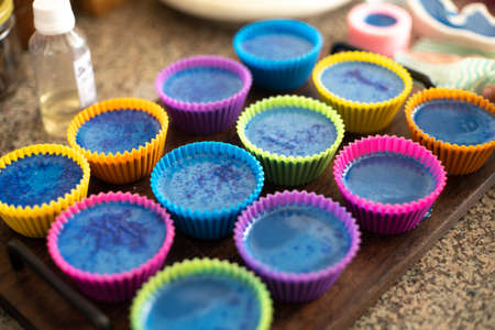 Colorful silicon cupcake molds on wooden coard filled with liquid soap for a home made hobby of melt and pour soapmakingの写真素材