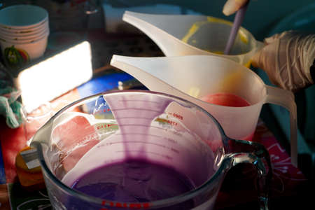 Purple solution batter soap base in a transparent glass jar and semi white plastic spout jars for...