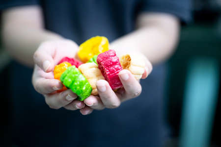 Young indian woman holding colorful fried food made of potato starch and sago called far far fryums which is a popular food in north india or a great snack. Shows an unhealthy fried snack with high empty calories that add to fat and heart diseaseの写真素材