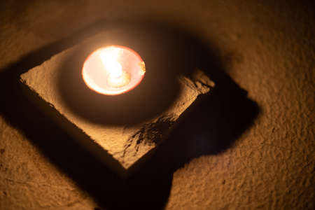 Top down shot showing a diya oil lamp filled with oil and a cotton wick burning placed in a dark room chasing away darkness with its light on the hindu festival of diwali dusseraの写真素材