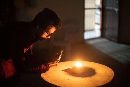 Man woman taking low light pictures of a diya oil lamp with a mobile phone for sharing images on the hindu festival of diwaliの写真素材