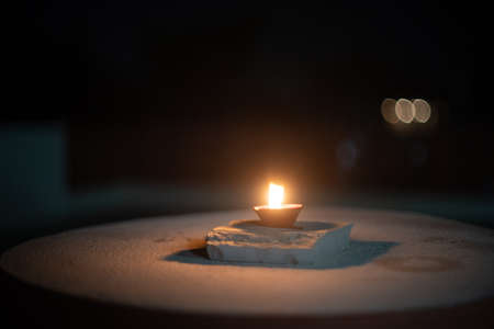 dark minimalistic image showing a diya oil lamp filled with oil or ghee and burning a cotton wick to produce a flame, its a popular religious item and decoration item on the hindu festival of diwaliの写真素材