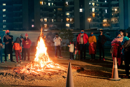 Men women families standing around giant blazing wood fire on lohri holi festival in indiaのeditorial素材