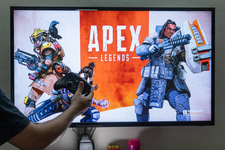Man holding steam controller in front of a screen loading apex legends a massively online multiplayer shooter game with millions of followersのeditorial素材