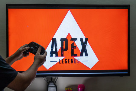 Man holding steam controller in front of a screen loading apex legends a massively online multiplayer shooter game with millions of followersのeditorial素材