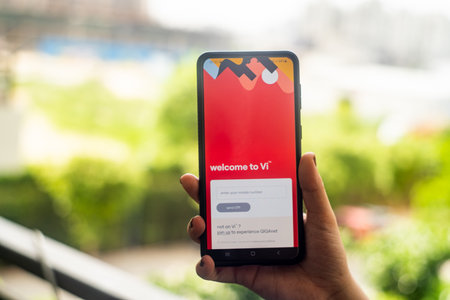 Woman holding a mobile phone against urban background with vodafone Idea VI  indias telecom operator which has been strugglingのeditorial素材