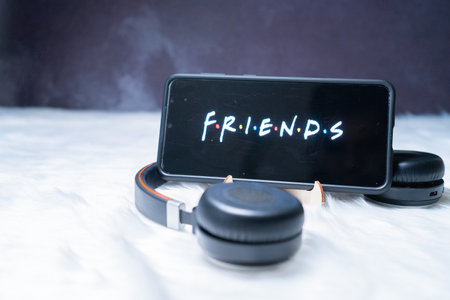 mobile smartphone on stand with headphones near it placed on a fur snow surface binge watching Friends popular netflix showのeditorial素材