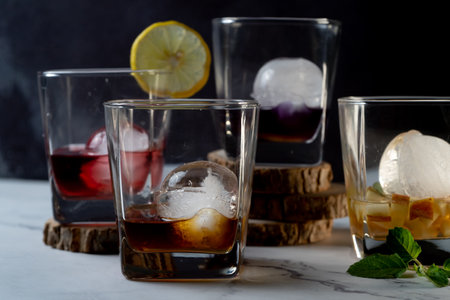 multiple whiskey glasses filled with different colored infused mulled wine gin rum vodka drinks with ice balls and wedges of lime, mint showing the hobby of gin infusion at home as a celebration drinkの写真素材