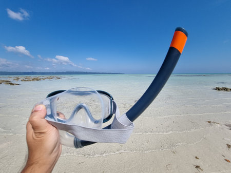 Panning shot holding out a snorkeling mask and breathing tube while going from the beach to the blue green waters at kala pathar beach andaman nicobar island Indiaの写真素材