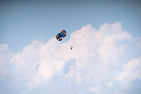 para sailing gliding under colorful parachute canopy hanging with bare legs in harness against a cloudy dusk sky in the windy weather showing adventure water sports in Havelock Andaman Nicobar island India asiaの写真素材