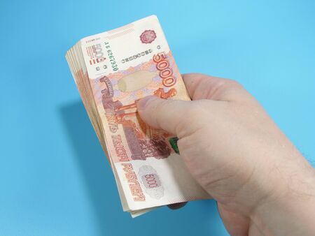 Man's hand holding stack of Russian 5000 rubles banknotes