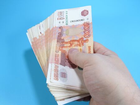 Man's hand holding stack of Russian 5000 rubles banknotes