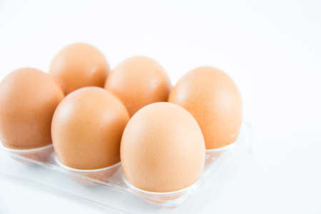 Six brown eggs in a case put on white background.の写真素材