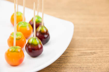 Deletable imitation fruits in white plate on brown wood background.の写真素材