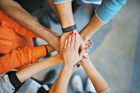 Closeup of stack of hands. Young college students putting their hands on top of each other symbolizing unity and teamwork. Closeup of stack of hands. Young college students putting their hands on top of each other symbolizing unity and teamwork.