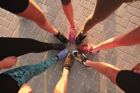 Legs of athletes wearing sports shoes in a circle. Top view of runners standing together. Legs of athletes wearing sports shoes in a circle. Top view of runners standing together.