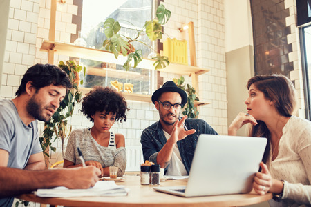 Portrait of creative business team sitting at a coffee shop with laptop. Young man discussing new business ideas with colleagues at a cafe. Portrait of creative business team sitting at a coffee shop with laptop. Young man discussing new business ideas with colleagues at a cafe.