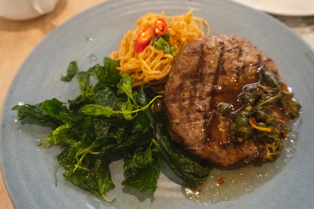 Grilled beef steak with spinach and chili sauce on a blue plateの写真素材