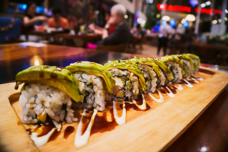 Sushi roll with avocado on a wooden board in a restaurant.の写真素材
