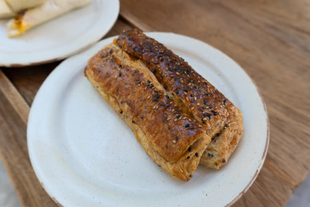 Sausage roll with sesame seeds on white plate, stock photo
