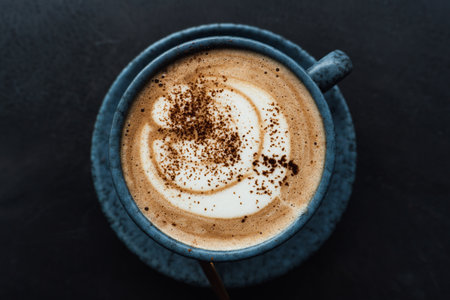 Coffee cappuccino in a blue cup on a black backgroundの写真素材