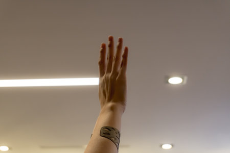Hands of a young man with tattoo on his arm and light bulb in the backgroundの写真素材