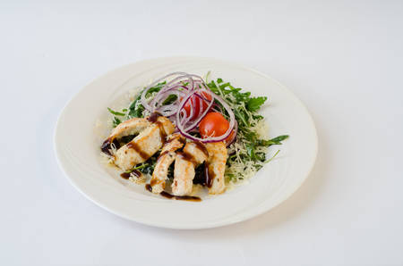 chicken salad with arugula, onion and sauce on the plateの写真素材