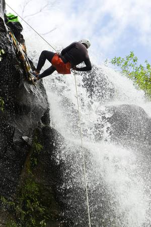 Man desceding a huge waterfall in Ecuadorian rain forest の写真素材