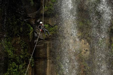 adult man desceding an ecuadorian waterfall in a corect position