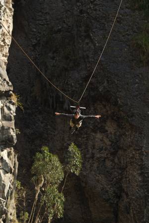 young man having fun during a zipline flight in banos de agua santa, ecuador.