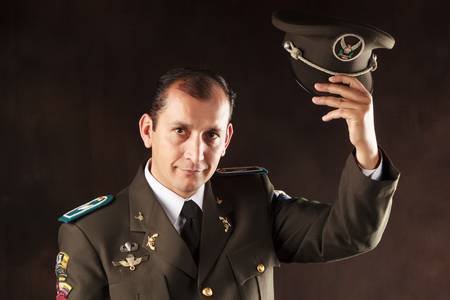 ecuadorian police official dressed up in formal uniform saluting, studio shot.