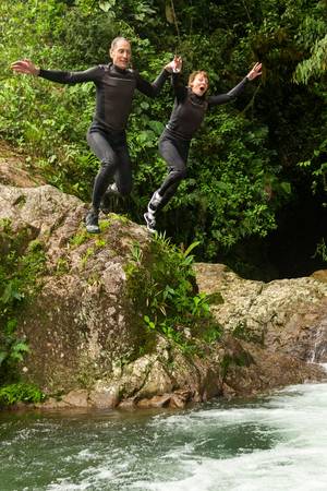Couple of seniors jumping into a natural pool, Llanganates national park , Ecuador.の写真素材