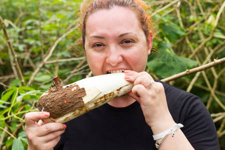 Hungry tourist woman with peeled cassava root