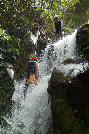 Professional Canyoning Guide Assisting A Tourist For A Waterfall Descent In Ecuadorian Andesの写真素材