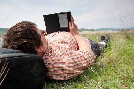 Guy Laying On The Grass And Reading A Book