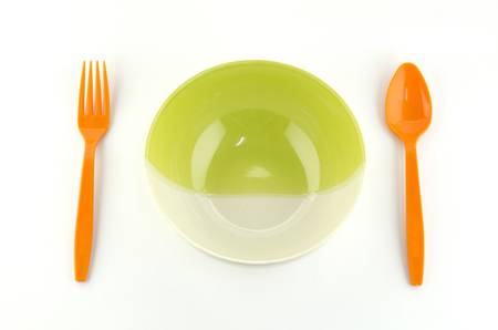 green white bowl with orange spoon and fork isolated on white backgroundの写真素材