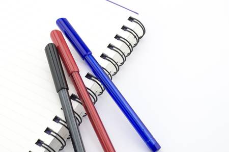 black red and blue pen with notebook isolated on white backgroundの写真素材