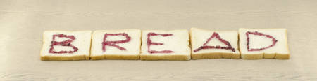 jam alphabet on sliced bread on wood background